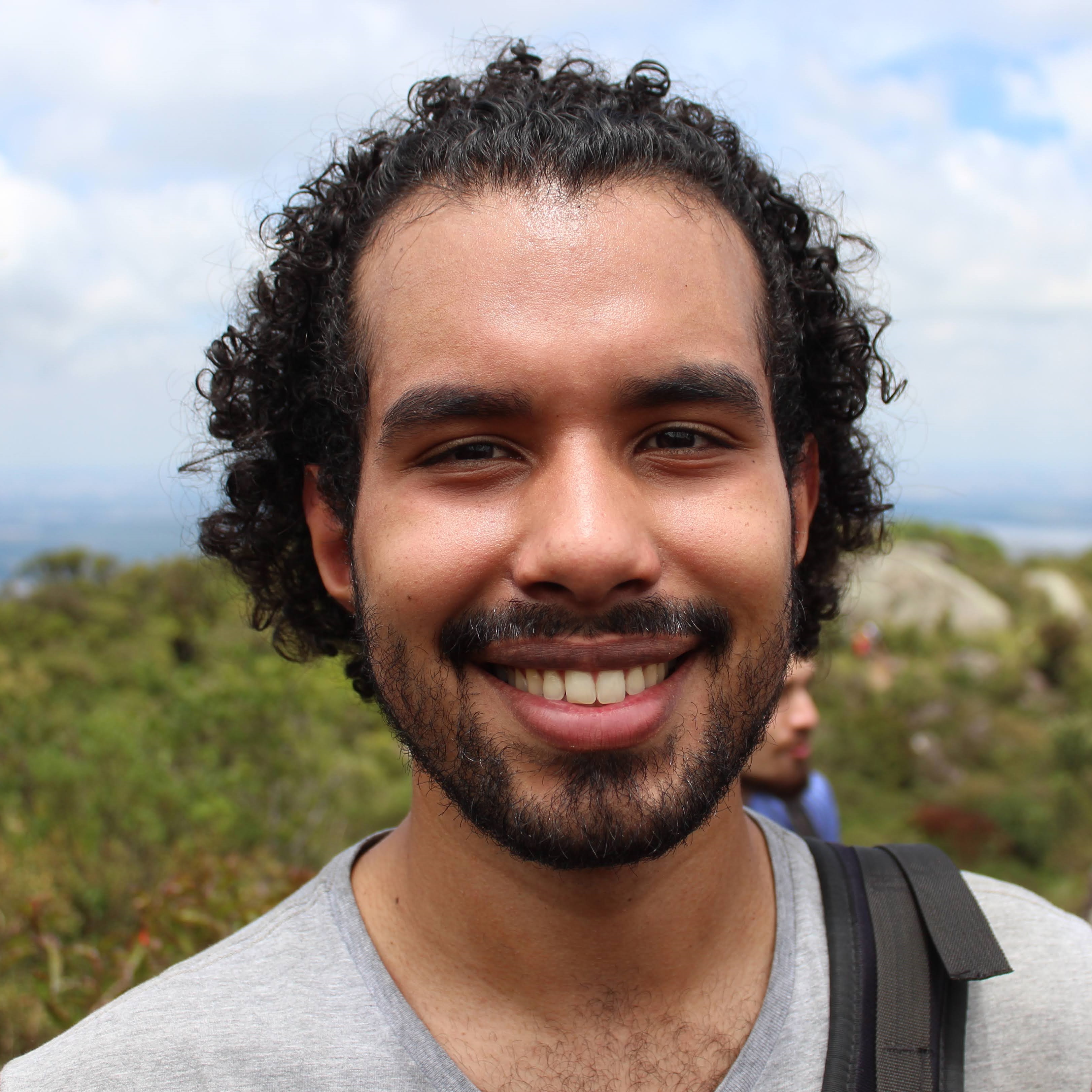 o rosto de um homem sorrindo com um fundo de vegetação
